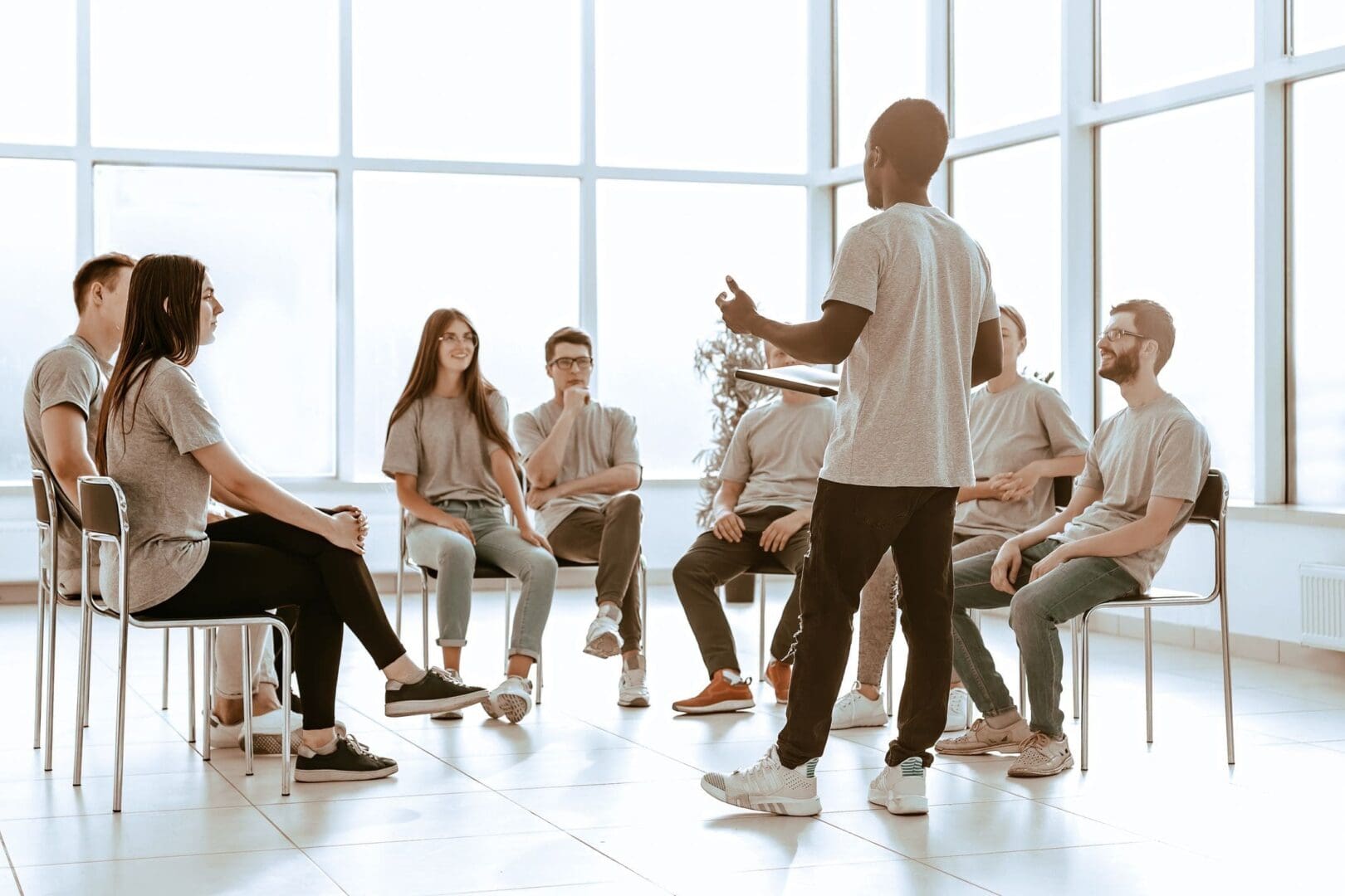 A person leading a discussion with a group seated in a bright room.